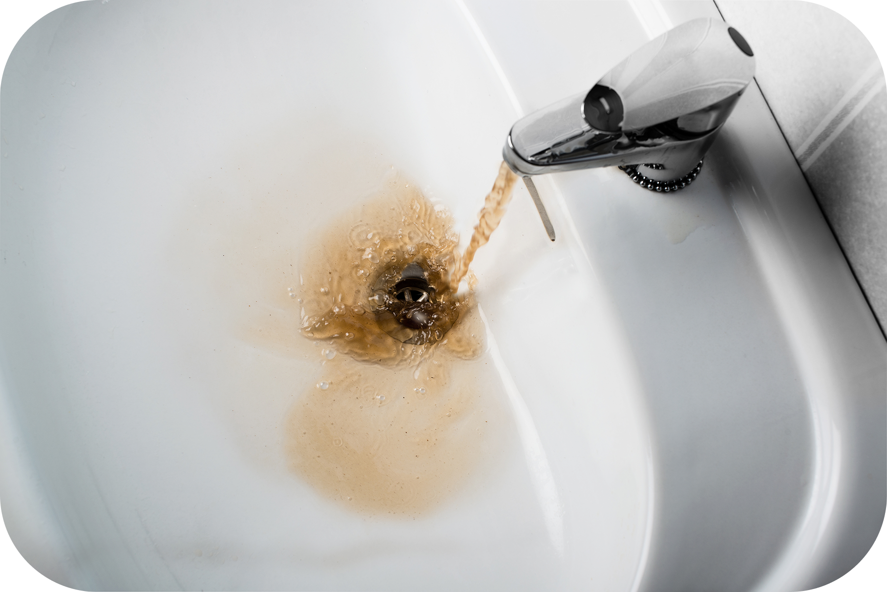 Bathroom sink shows dirty, rusty brown water typical with iron and sediment in water.